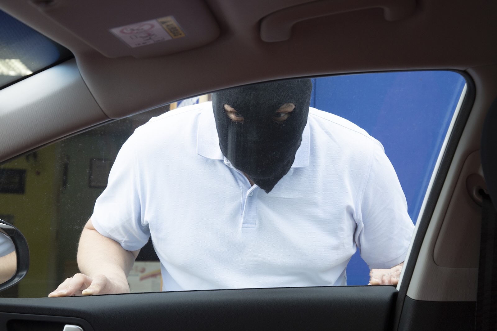 Car thief trapped outside of a Kia with the Hyundai software upgrade, wearing a black mask