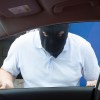 Car thief trapped outside of a Kia with the Hyundai software upgrade, wearing a black mask