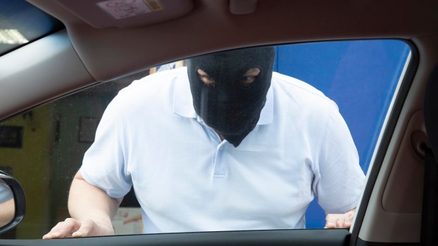 Car thief trapped outside of a Kia with the Hyundai software upgrade, wearing a black mask