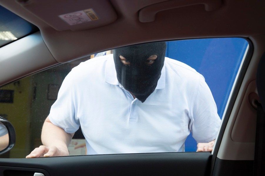 Car thief trapped outside of a Kia with the Hyundai software upgrade, wearing a black mask