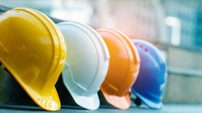 Row of multi-colored construction worker helmets hung up.