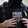 U.S. Customs and Border Protection ICE officer holding onto his vest.