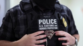 U.S. Customs and Border Protection ICE officer holding onto his vest.