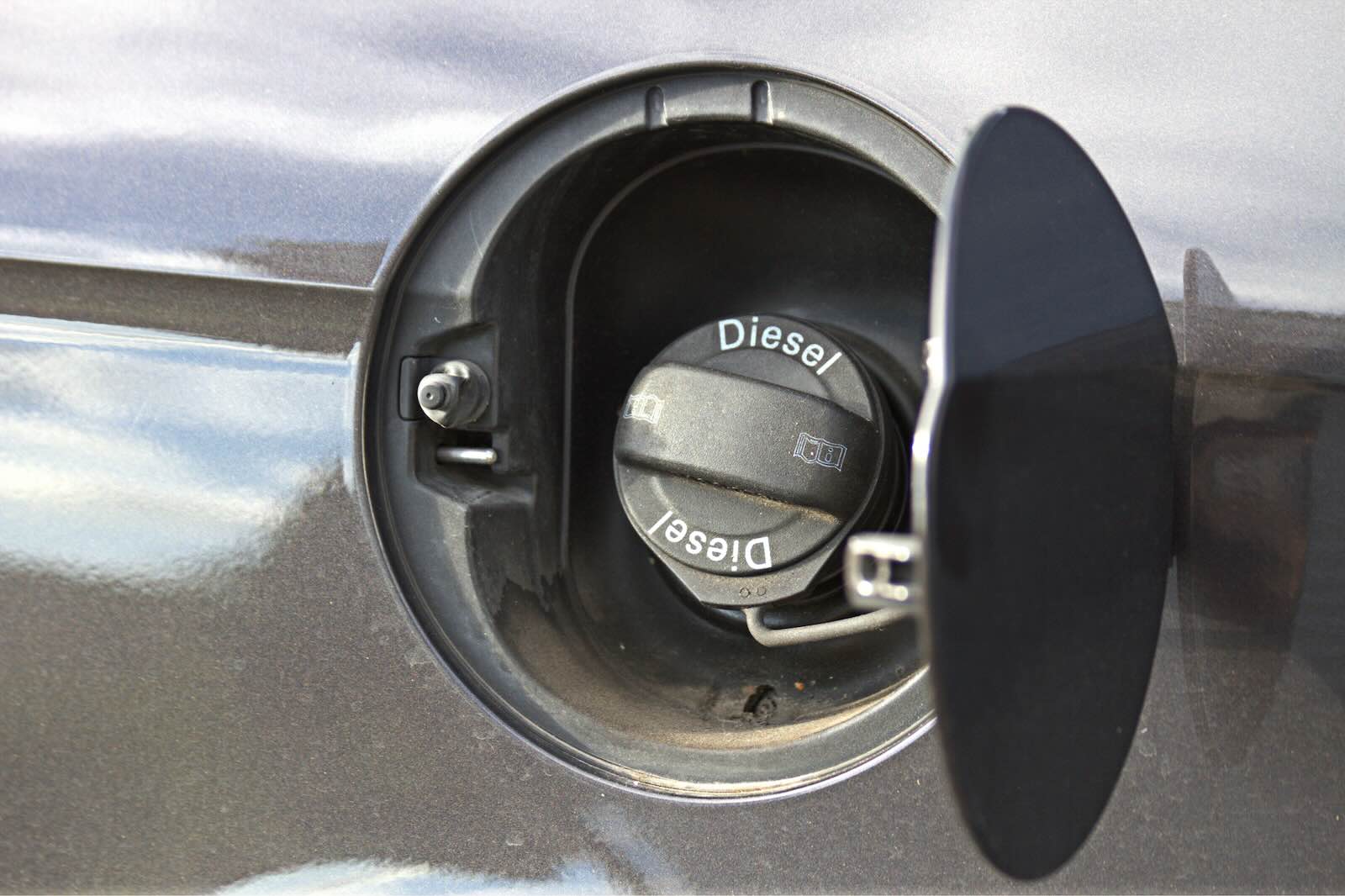 The fuel cap that says "diesel fuel" on a vehicle at a gas station.