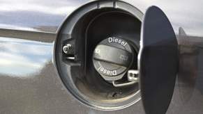The fuel cap that says "diesel fuel" on a vehicle at a gas station.