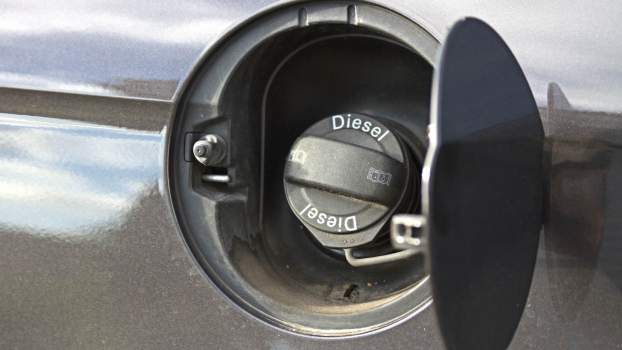 The fuel cap that says "diesel fuel" on a vehicle at a gas station.