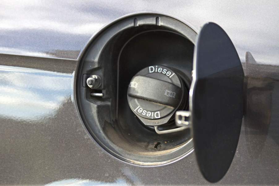 The fuel cap that says "diesel fuel" on a vehicle at a gas station.