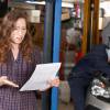 Woman holds Lexus dealership repair estimate in shock while mechanic works in the background.