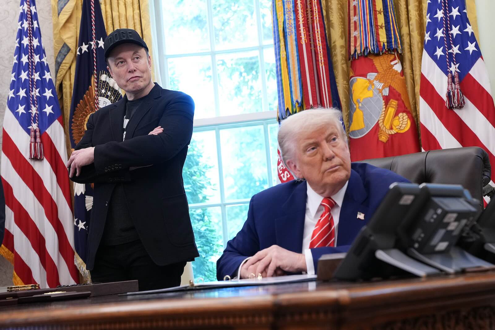 Elon Musk stands behind U.S. President Donald Trump in the Oval Office