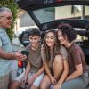 Family poses for a selfie on the tailgate of their SUV.