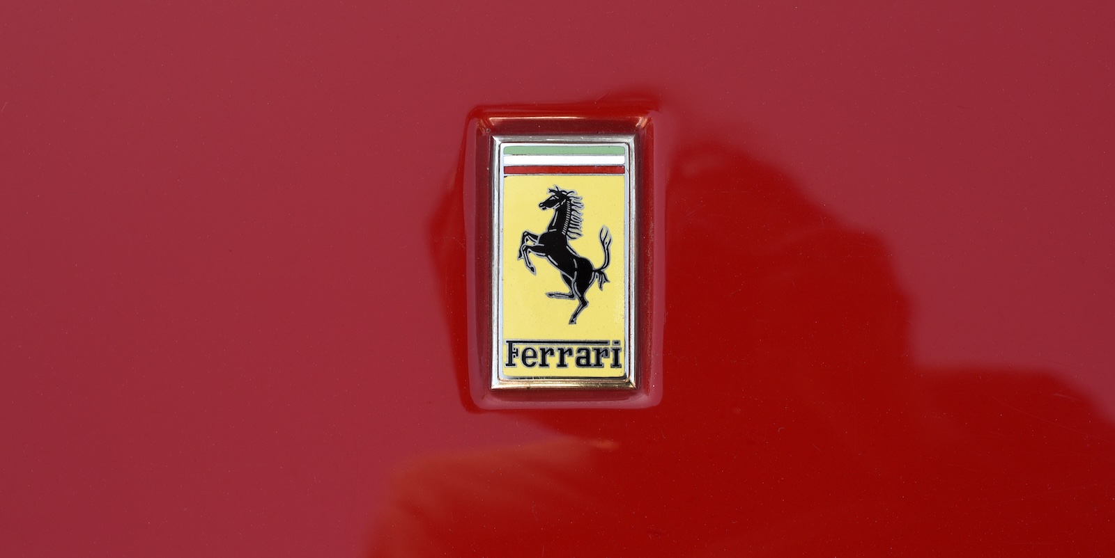 Yellow Ferrari logo on the hood of a red sports car.