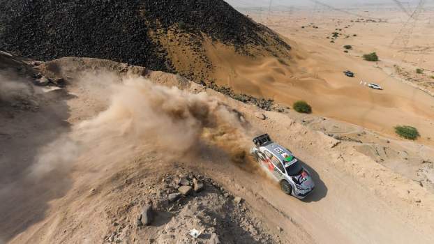 Overhead view of Toyota's Yaris rally car skidding through a mountain switchback during a race in Saudi Arabia.