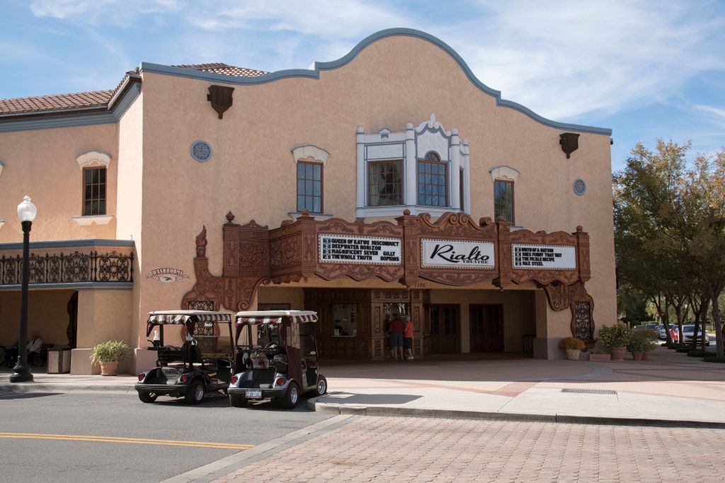 Two golf carts parked outside a movie theater on Main Street in a Florida town