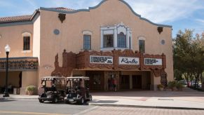 Two golf carts parked outside a movie theater on Main Street in a Florida town