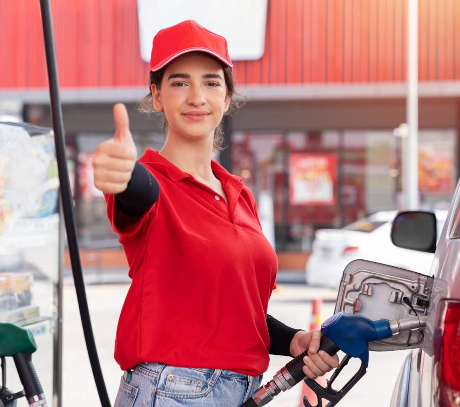 Happy driver fills efficient car at gas station.