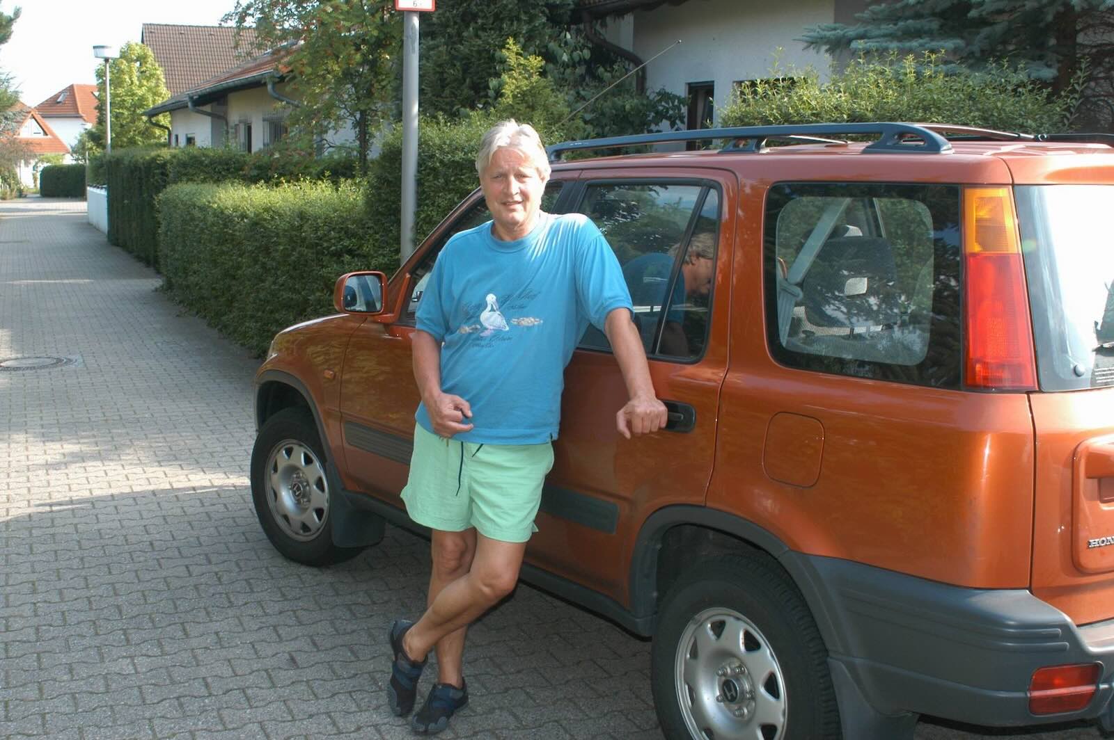 Man leaning against his vintage Honda CR-V crossover SUV