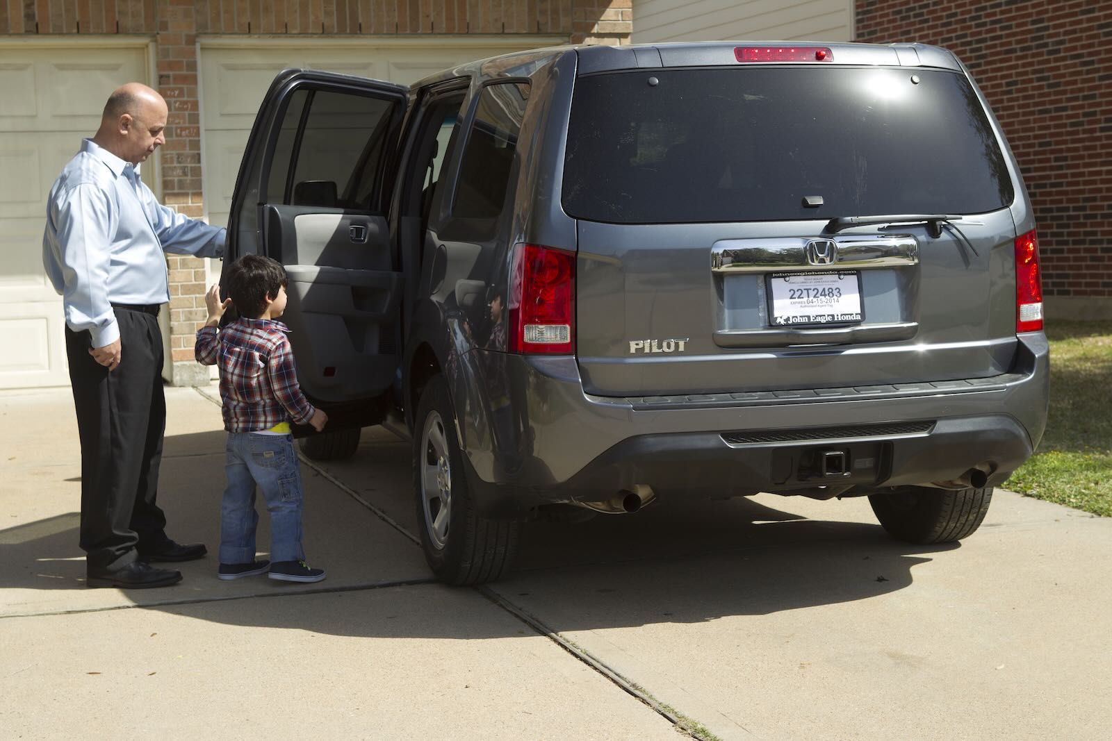 Man and his son stand next to a gray Honda Pilot SUV