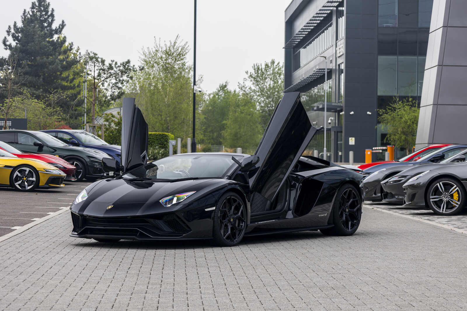 A black Lamborghini Aventador parked in far left angle view with its winged doors open
