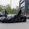 A black Lamborghini Aventador parked in far left angle view with its winged doors open