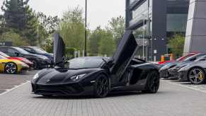 A black Lamborghini Aventador parked in far left angle view with its winged doors open