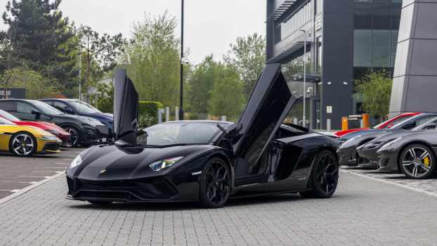 A black Lamborghini Aventador parked in far left angle view with its winged doors open
