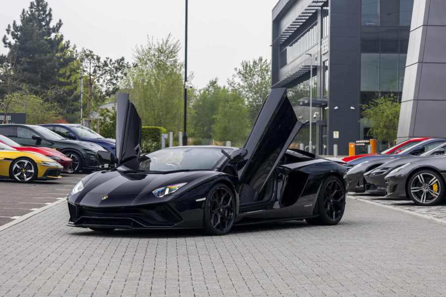 A black Lamborghini Aventador parked in far left angle view with its winged doors open