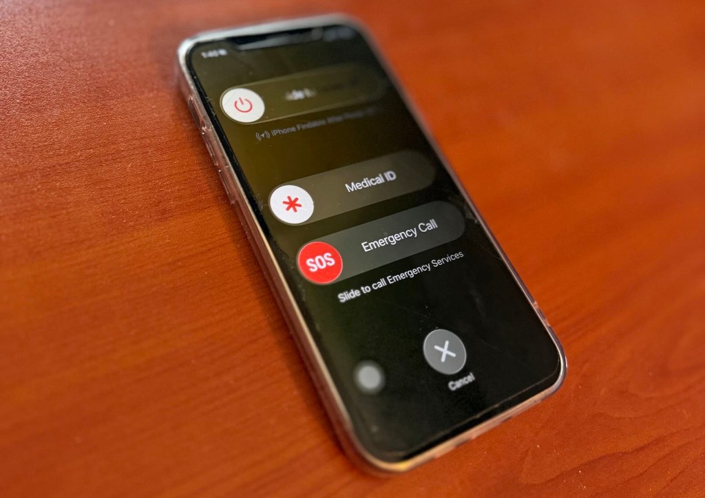 iPhone sitting on a wooden desk, its screen locked.