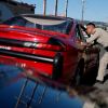 California Highway Patrol officer leans into the window of a red sport car during a traffic stop.