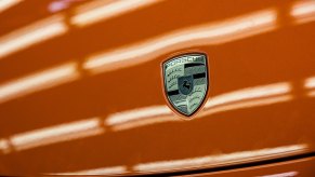 The Porsche Logo on a bright orang hood