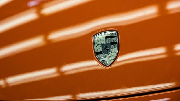 The Porsche Logo on a bright orang hood