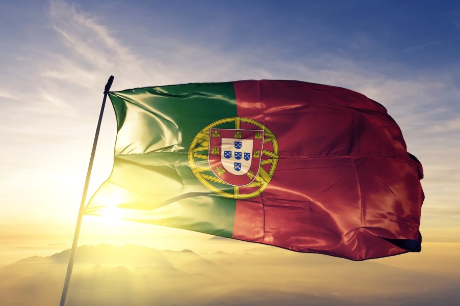 the Portuguese national flag waving in front of a sunset