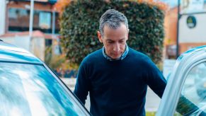 Man studies the inside of his car door, with the door open.