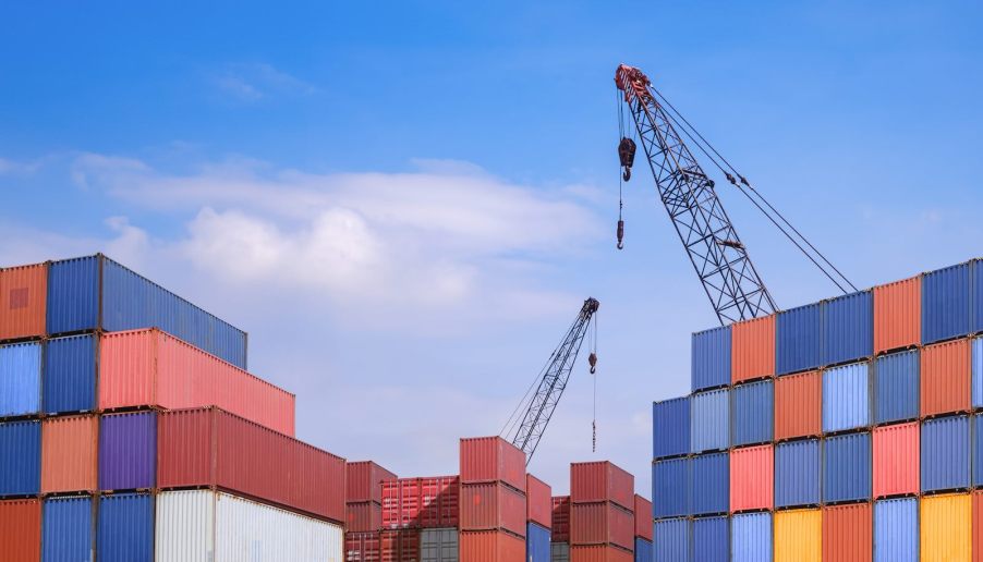 Tall st asks of shipping containers with cranes visible in the background.