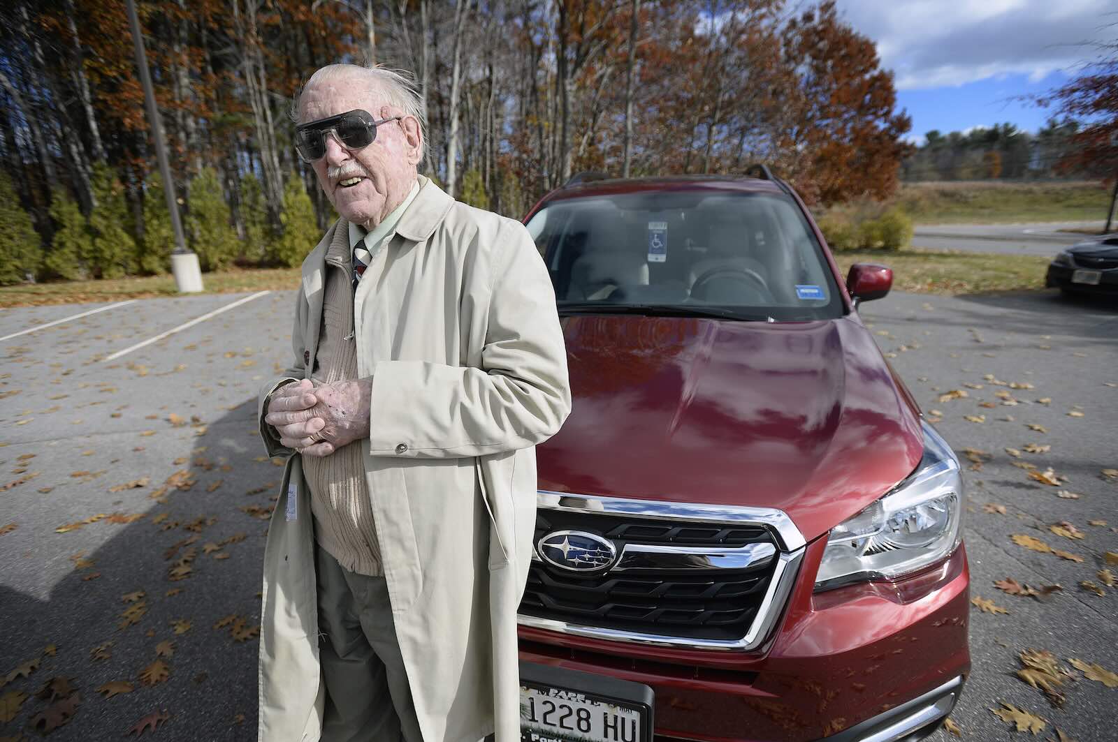 Old man standing in front of his brand new red Subaru Forester SUV.