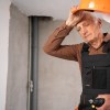 Tired construction worker takes off his helmet to wipe his forehead.