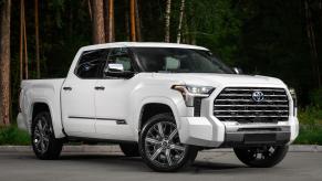 White Toyota Tundra pickup truck parked in front of a forest.