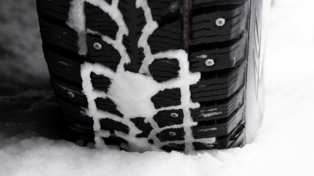 Winter tires on a snowy road, snow packed into their treads.