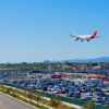 An airport parking lot with commercial jet flying over