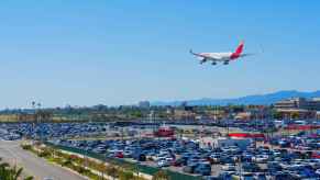 An airport parking lot with commercial jet flying over