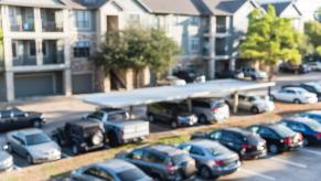 A blurred image of an apartment complex and parking lot