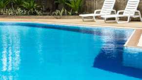 Blu water pool with two white loungers