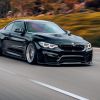A black BMW M4 driving fast on a highway in right front angle view