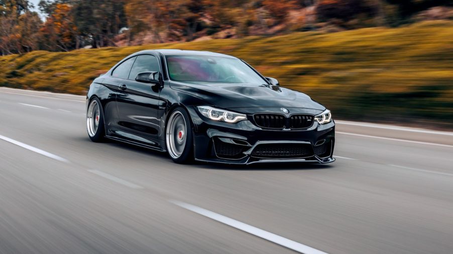 A black BMW M4 driving fast on a highway in right front angle view