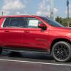 A red Chevrolet Suburban parked at a dealership in right side view