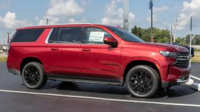 A red Chevrolet Suburban parked at a dealership in right side view