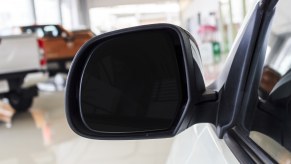 A Chevrolet dealership showroom in blurred background with left side mirror in foreground