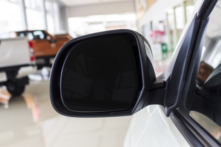 A Chevrolet dealership showroom in blurred background with left side mirror in foreground