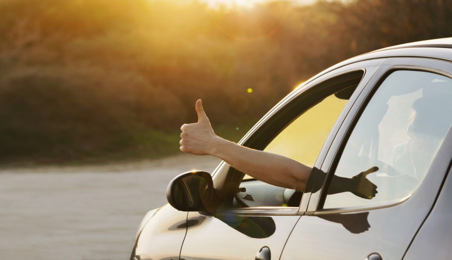 A depiction of a rental car driver giving a thumbs up out their window at dusk