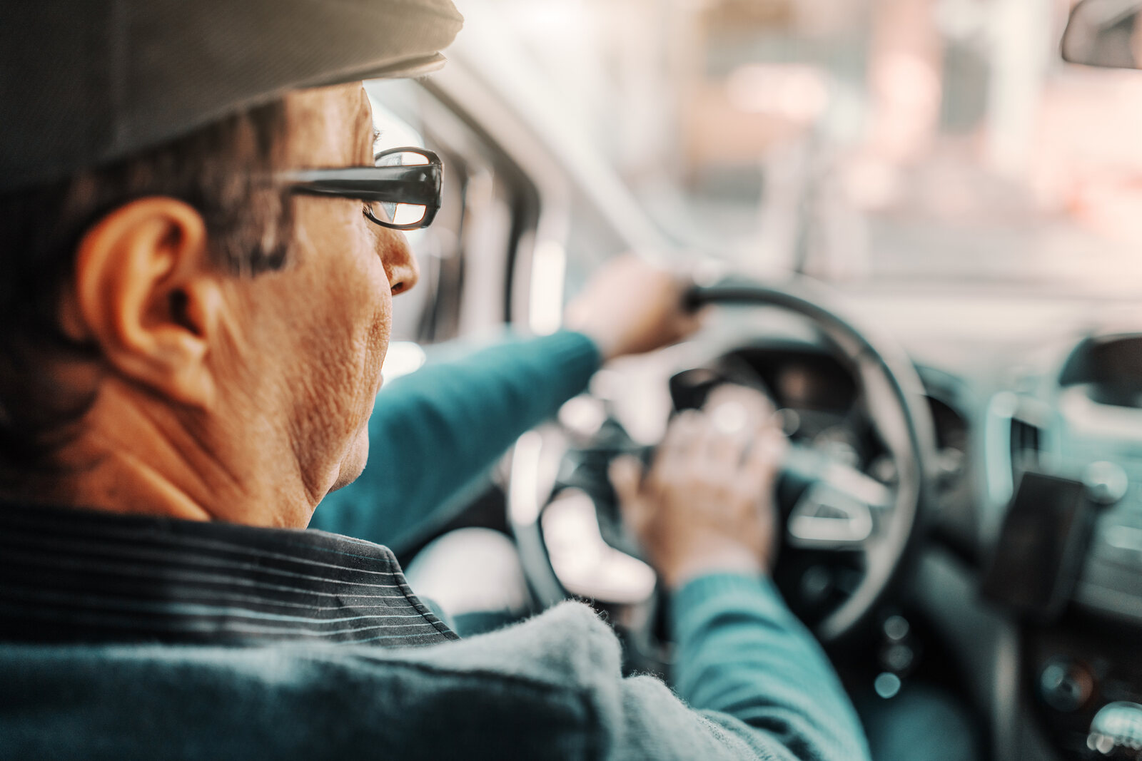 An elderly driver, view from backseat