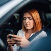 A female driver scrolling on her cell phone